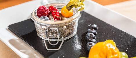 Uma sobremesa com frutas vermelhas e uma fruta em um prato preto.