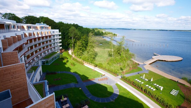 Un hôtel doté de nombreux balcons donnant sur un lac, d’une pelouse bien entretenue et d’une jetée s’avançant dans l’eau.