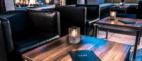 A modern restaurant interior with leather seating, wooden tables, and a fireplace.
