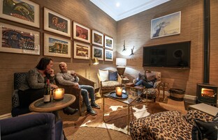 A cozy lounge area with leather sofas, a fireplace, and artwork on the walls.