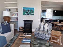 A living room with a fireplace, a sofa, a patterned armchair, a coffee table, and a bookshelf.