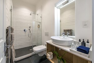 A modern bathroom with a glass-enclosed shower, a white sink, and a large mirror.
