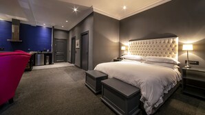 Quarto de hotel moderno com uma cama grande, mesas de cabeceira, uma escrivaninha e uma cadeira.