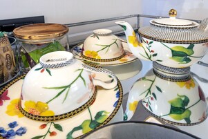 A display of white porcelain tea sets with floral designs and gold trim.