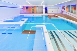 A large indoor swimming pool with multiple lanes, safety markings, and a changing room area. - Apartamentos Dynastic Rooms (Benidorm)