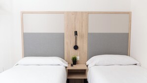 A double room with two single beds, a small bedside table with a lamp, and a potted plant. - Apartamentos Dynastic Rooms (Benidorm)
