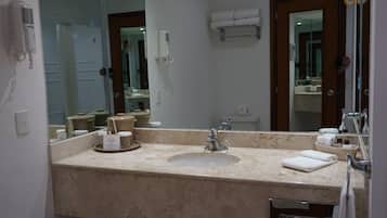 Un baño con un espejo grande, lavamanos, toallero y secador de pelo.