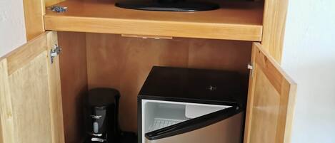 Ein Holzschrank mit Fernseher obenauf und einem Minikühlschrank darunter.