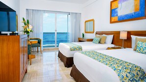 Une chambre d’hôtel avec deux lits, une télévision, un bureau et une vue sur l’océan.