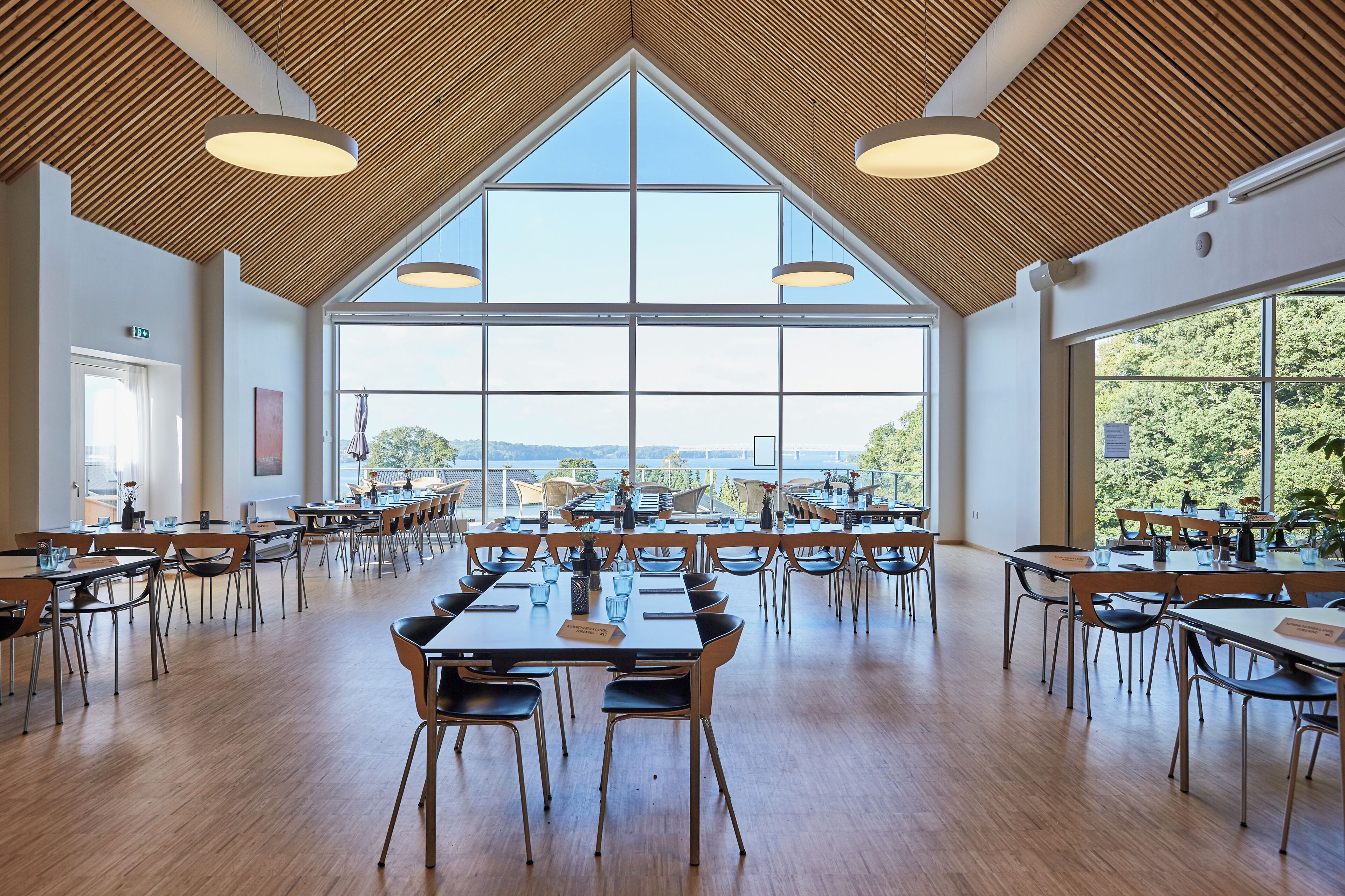 Un'ampia sala da pranzo con soffitti alti, ampie finestre e vista sull'esterno.