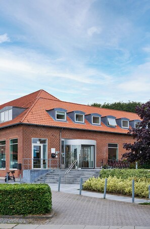 A modern building with a red-tiled roof, brick walls, and multiple windows.