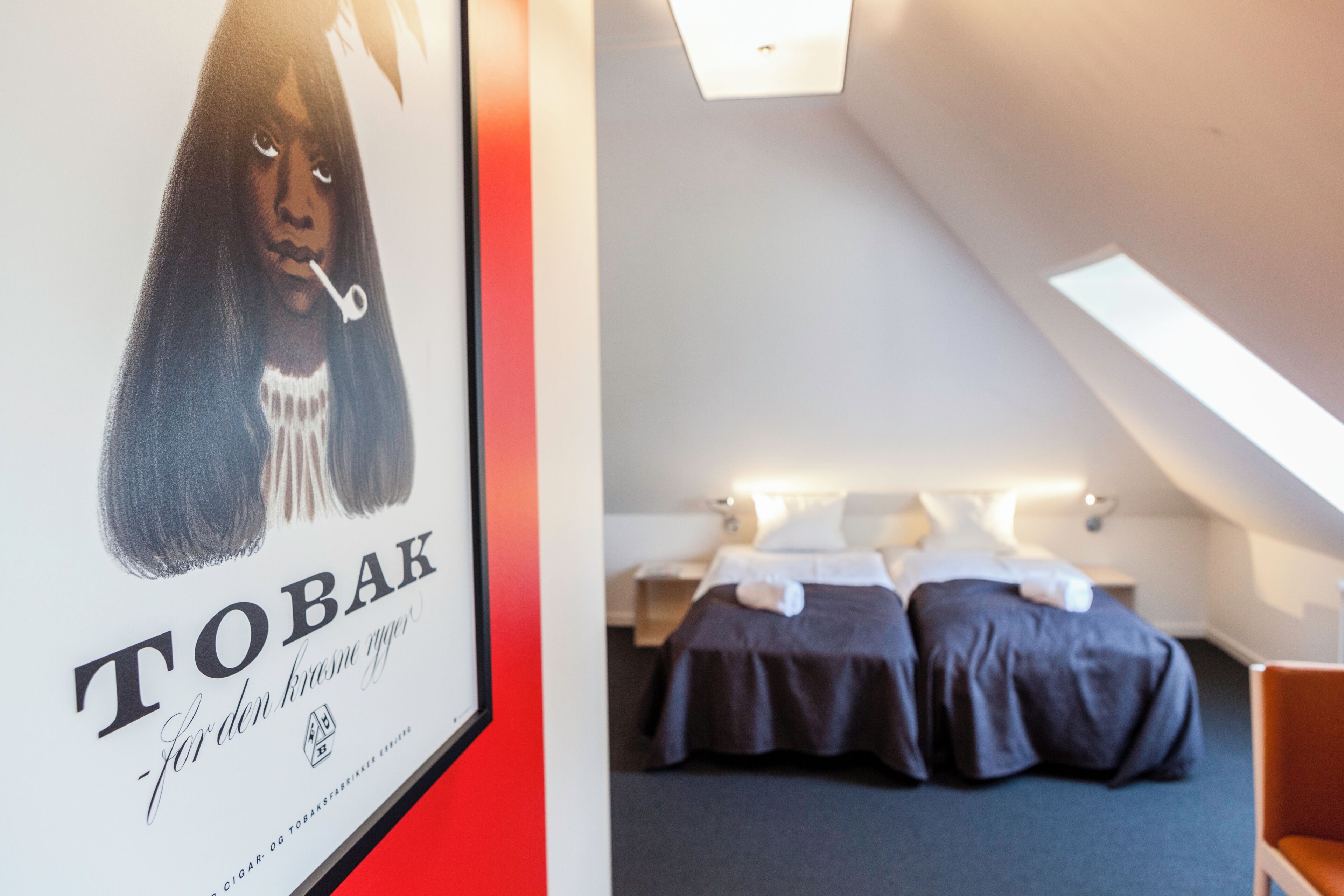 Een lijst met een poster met tekst, en een moderne hotelkamer met een bed en nachtkastje.
