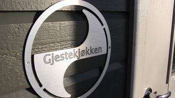 Un letrero metálico con la inscripción 'Gjestekjokken' en una puerta de madera.