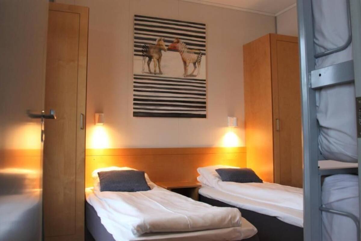 A hotel room with two single beds, a wooden headboard, a zebra painting, and a striped wall design.