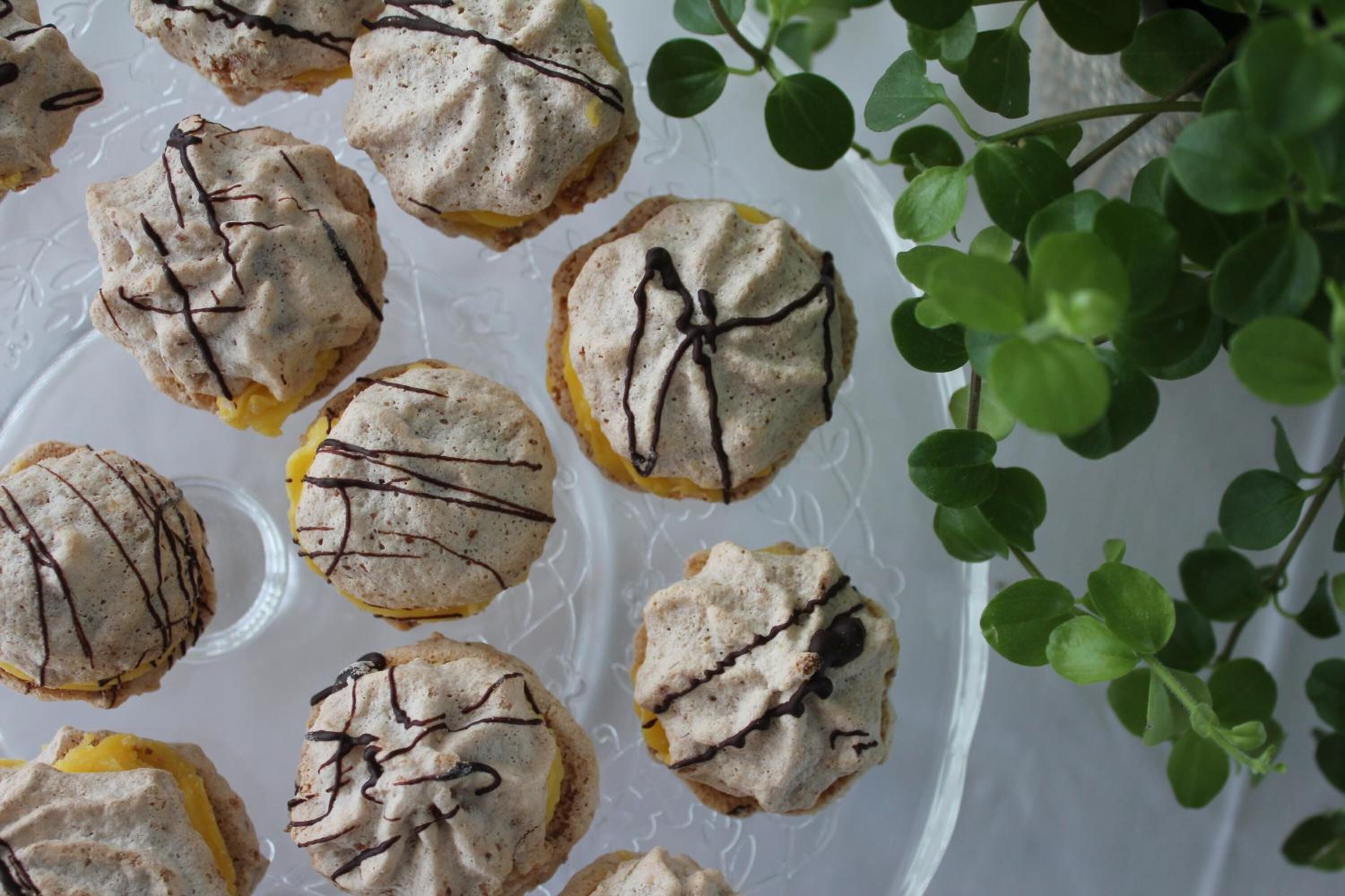 A tray of cookies with chocolate drizzle, placed on a clear glass plate.
