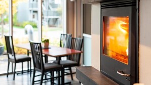 A modern outdoor seating area with a fireplace, a dining table, and chairs. - Vikingskipet Hamar Hostel & Apartments (Hamar)