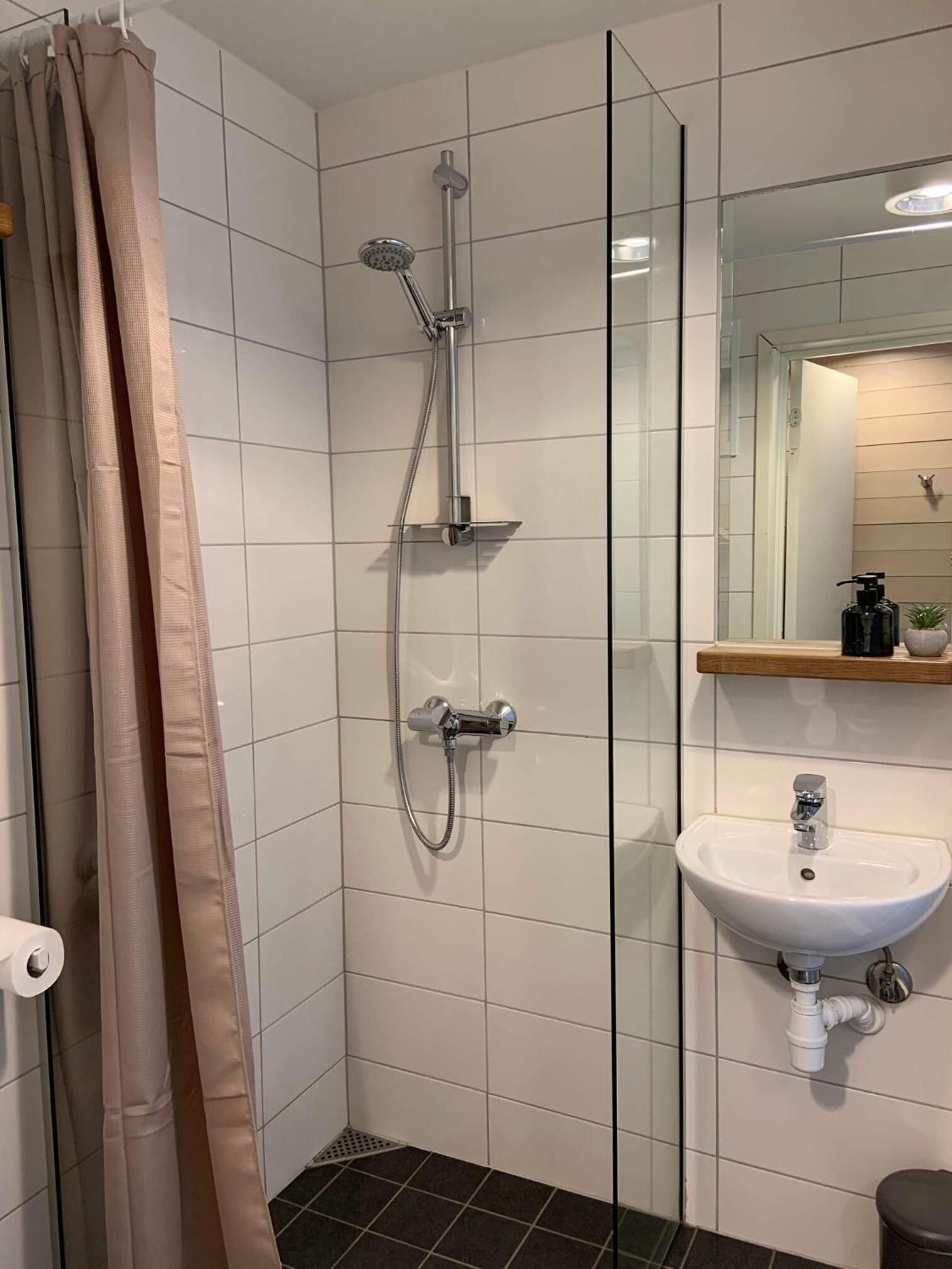 Un baño moderno con cabina de ducha de vidrio, un lavamanos blanco y un espejo sobre él.