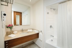 Un baño moderno con un espejo grande, un lavamanos, una bañera y un secador de pelo.