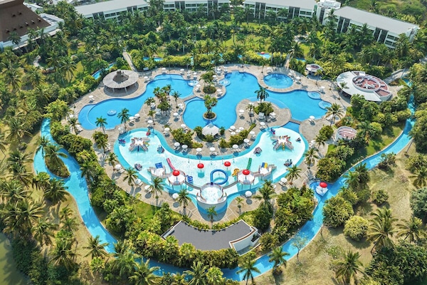 Una piscina al aire libre, sombrillas, sillones reclinables de piscina