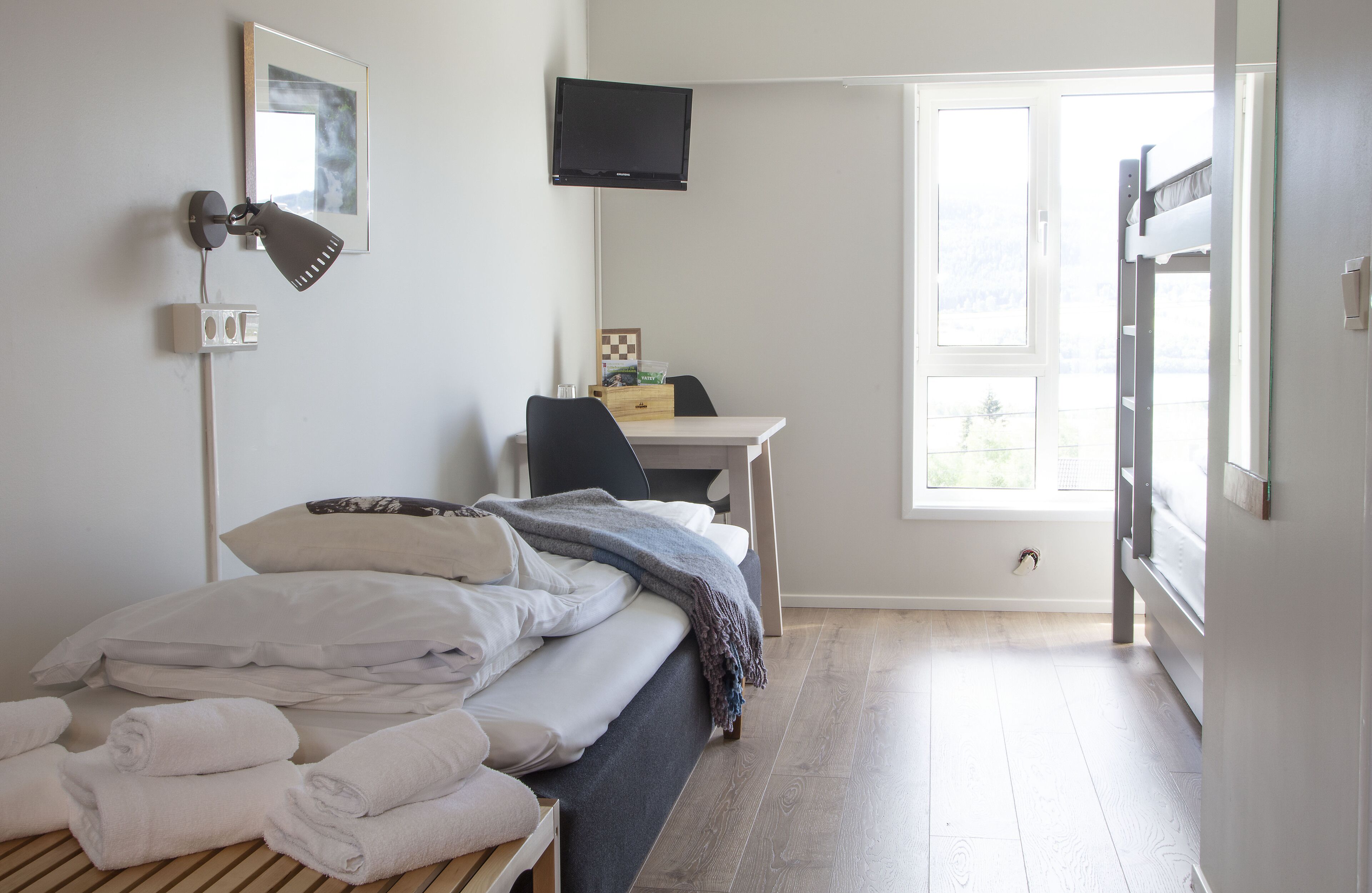 Ein Hotelzimmer mit Bett, Schreibtisch, Fernseher und Fenster.