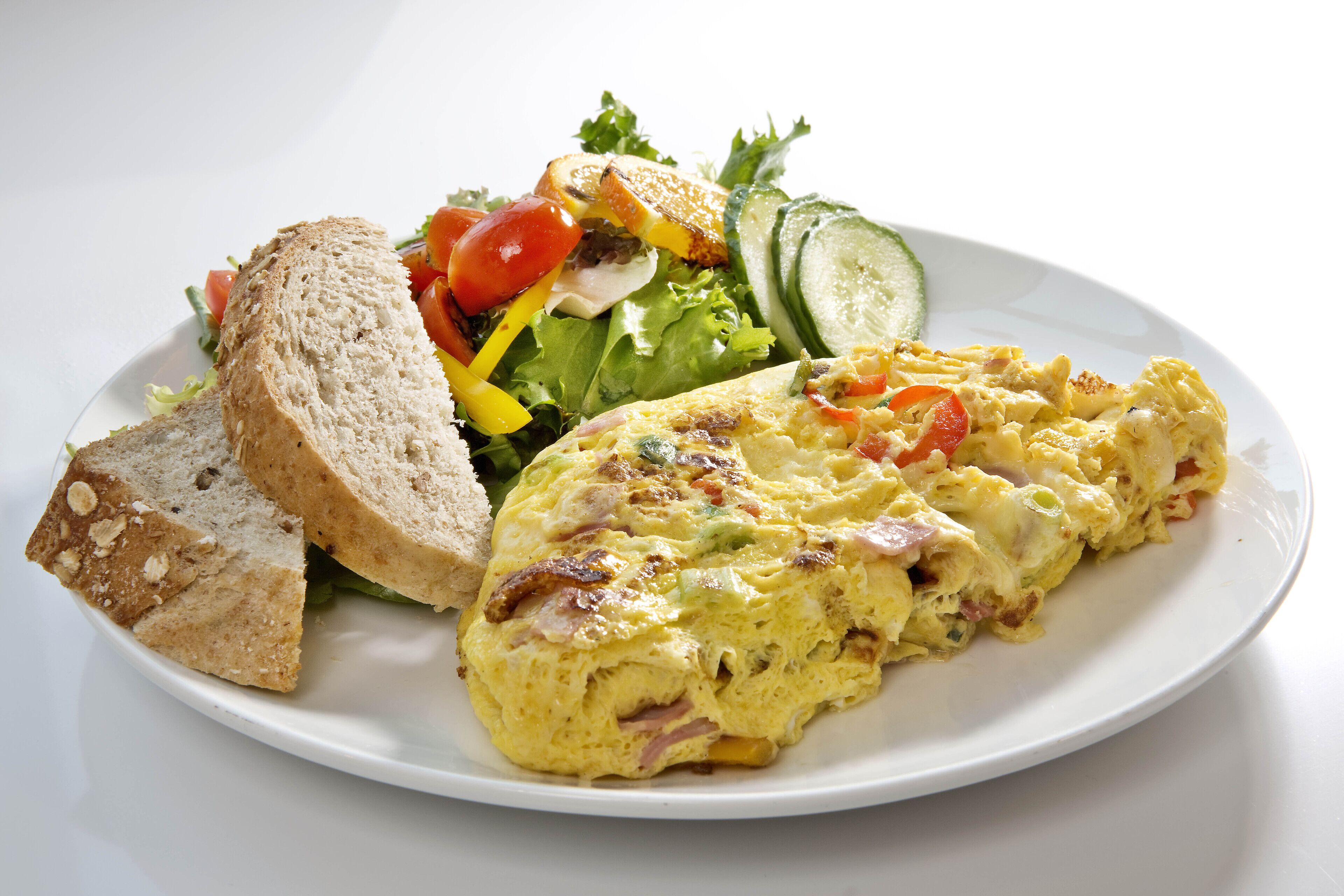 A plate with an omelette, a salad, and slices of bread.