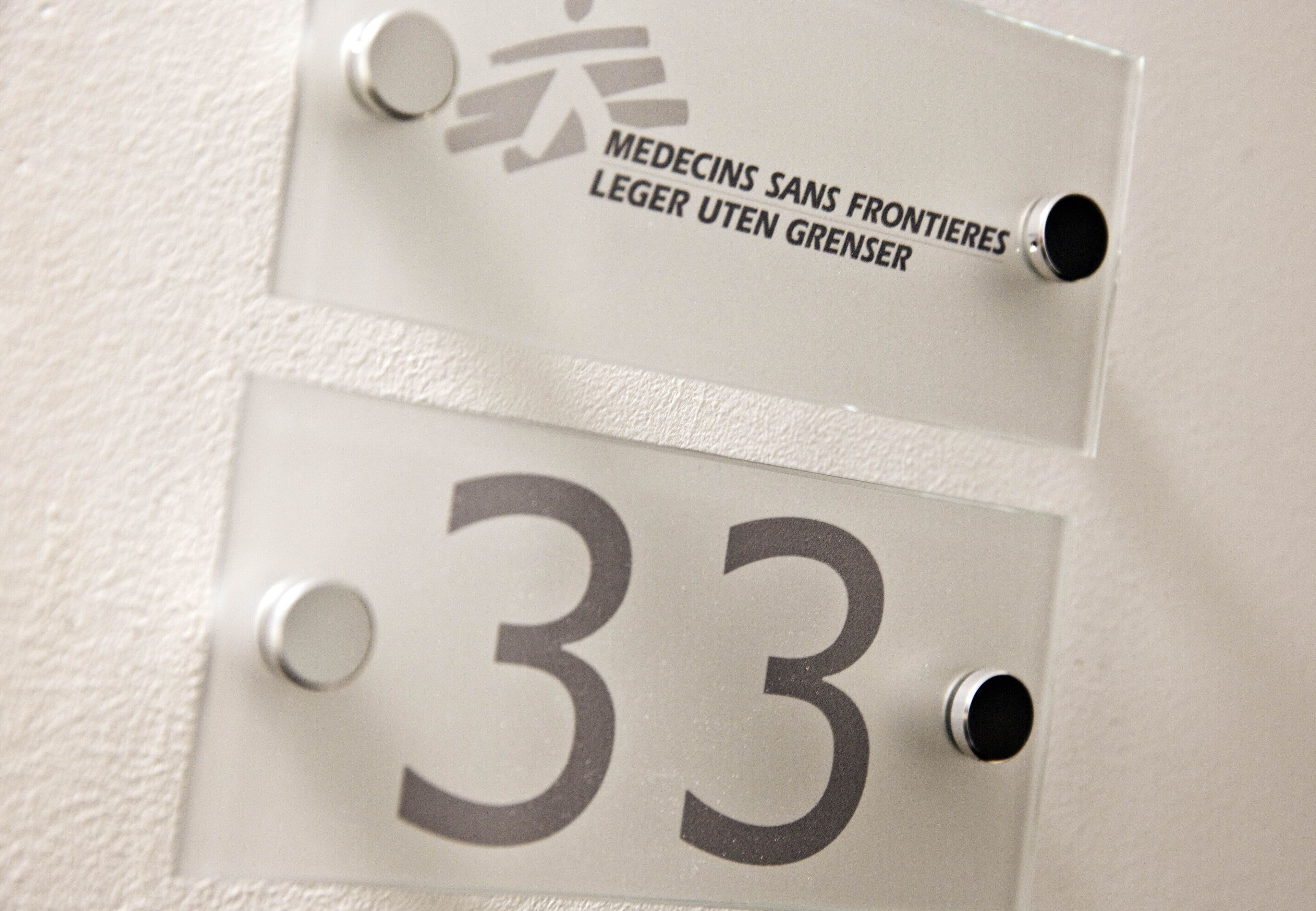 Primer plano de una pared con dos letreros: uno con el número '33' y otro con texto en un idioma extranjero.