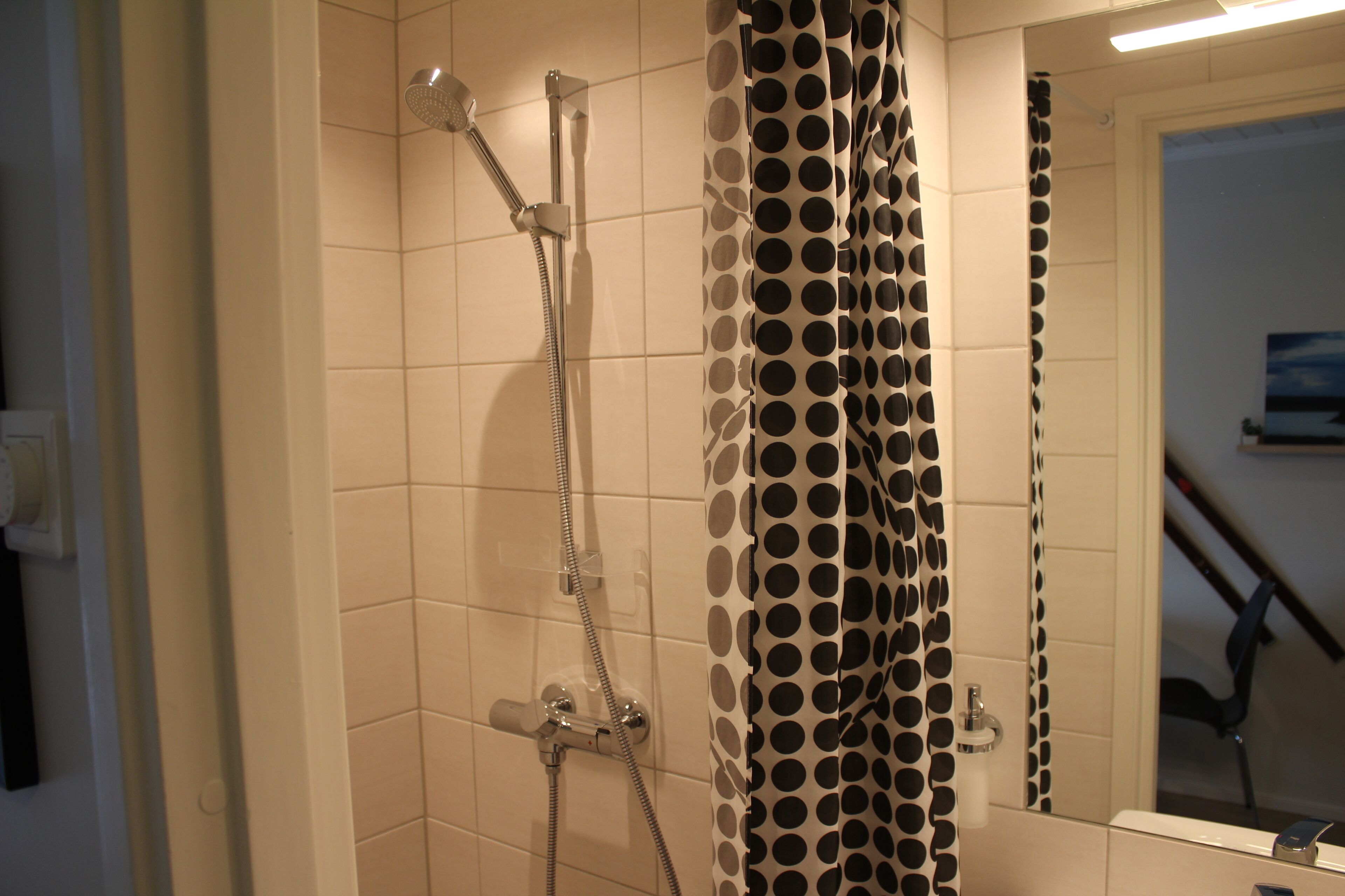 Un baño con ducha, inodoro y espejo.