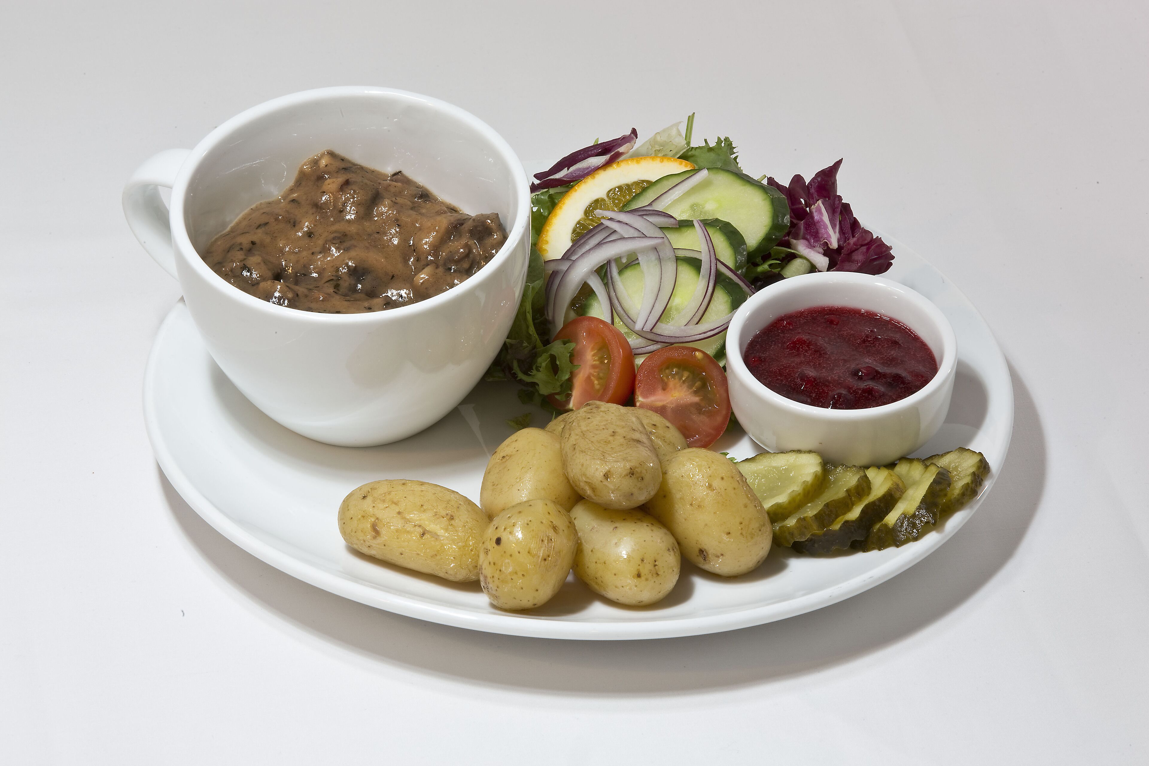 En tallerken med salat, en skål med sauce og kogte kartofler.