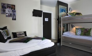 A dormitory room with bunk beds, a flat-screen TV, and various wall decorations including photos and posters.
