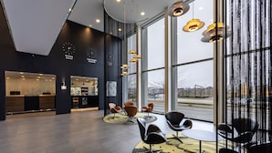 Un interior moderno con un mostrador de recepción, una zona de estar y grandes ventanales que ofrecen vistas al exterior.