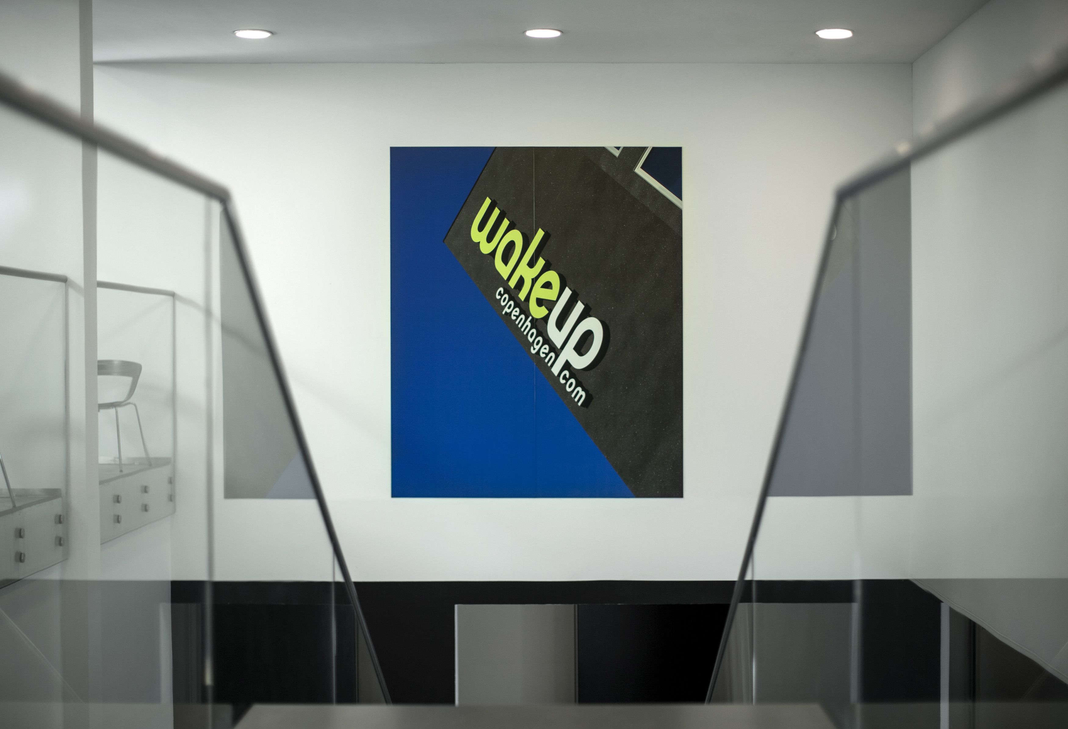 A modern interior with a large poster on the wall advertising 'wakeup Copenhagen.com'.