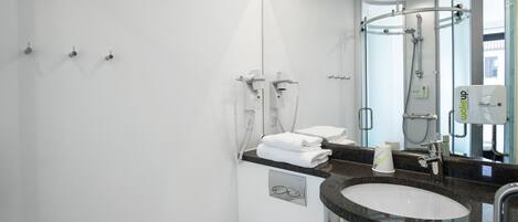 A modern bathroom with a large mirror, a sink, a toilet, and a shower.