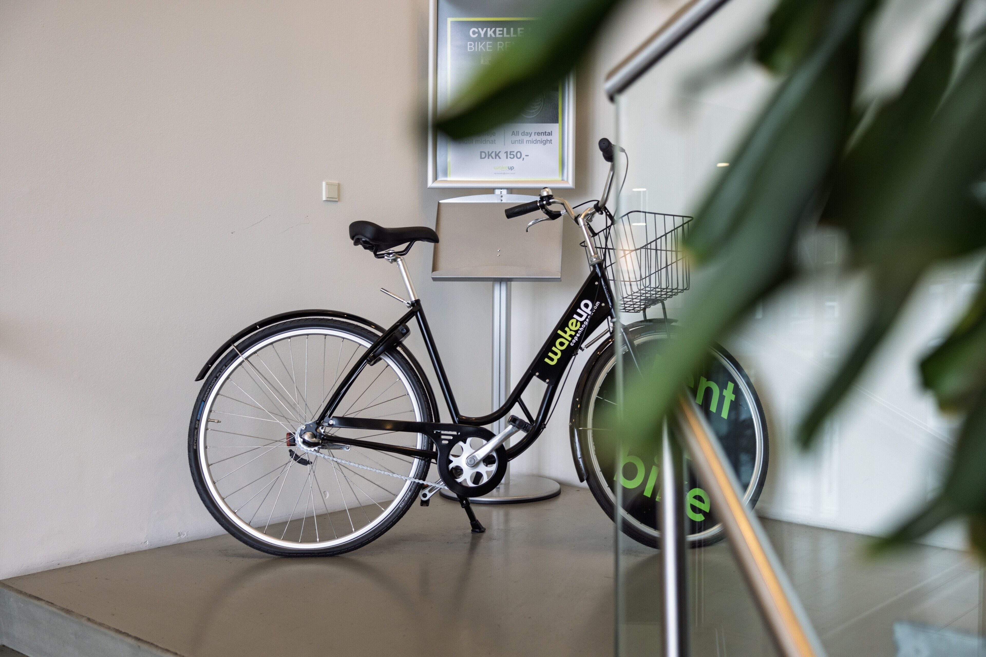 A bicycle parked indoors with a sign in the background.
