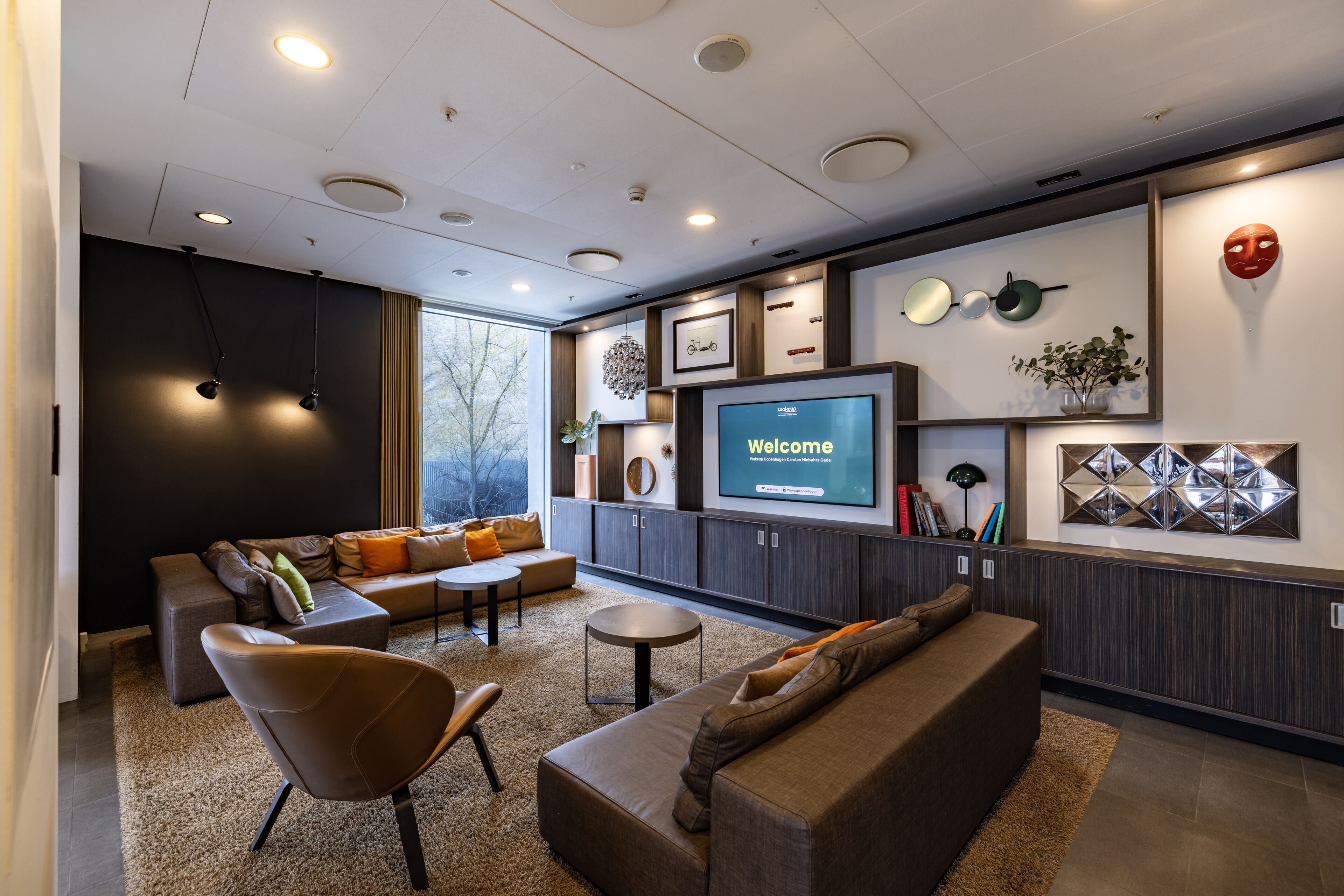 A modern living room with a large flat-screen TV displaying "Welcome," a sofa, a chair, and a coffee table.