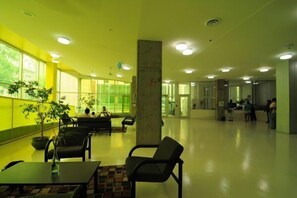 A spacious lobby with seating areas, large windows, and a central pillar.
