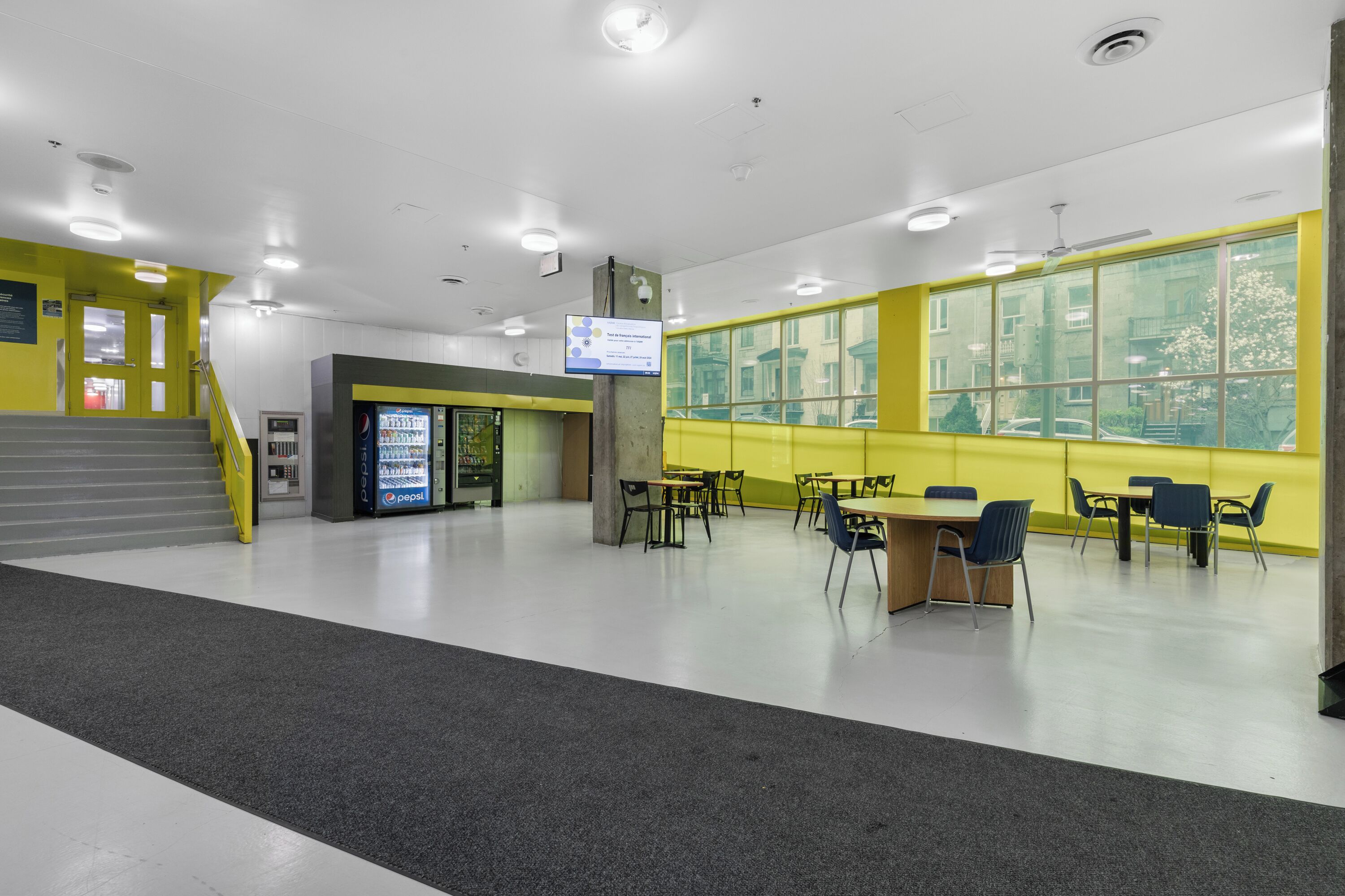 A spacious indoor area with a seating area, a vending machine, and a staircase.
