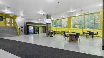A spacious indoor area with a seating area, a vending machine, and a staircase.