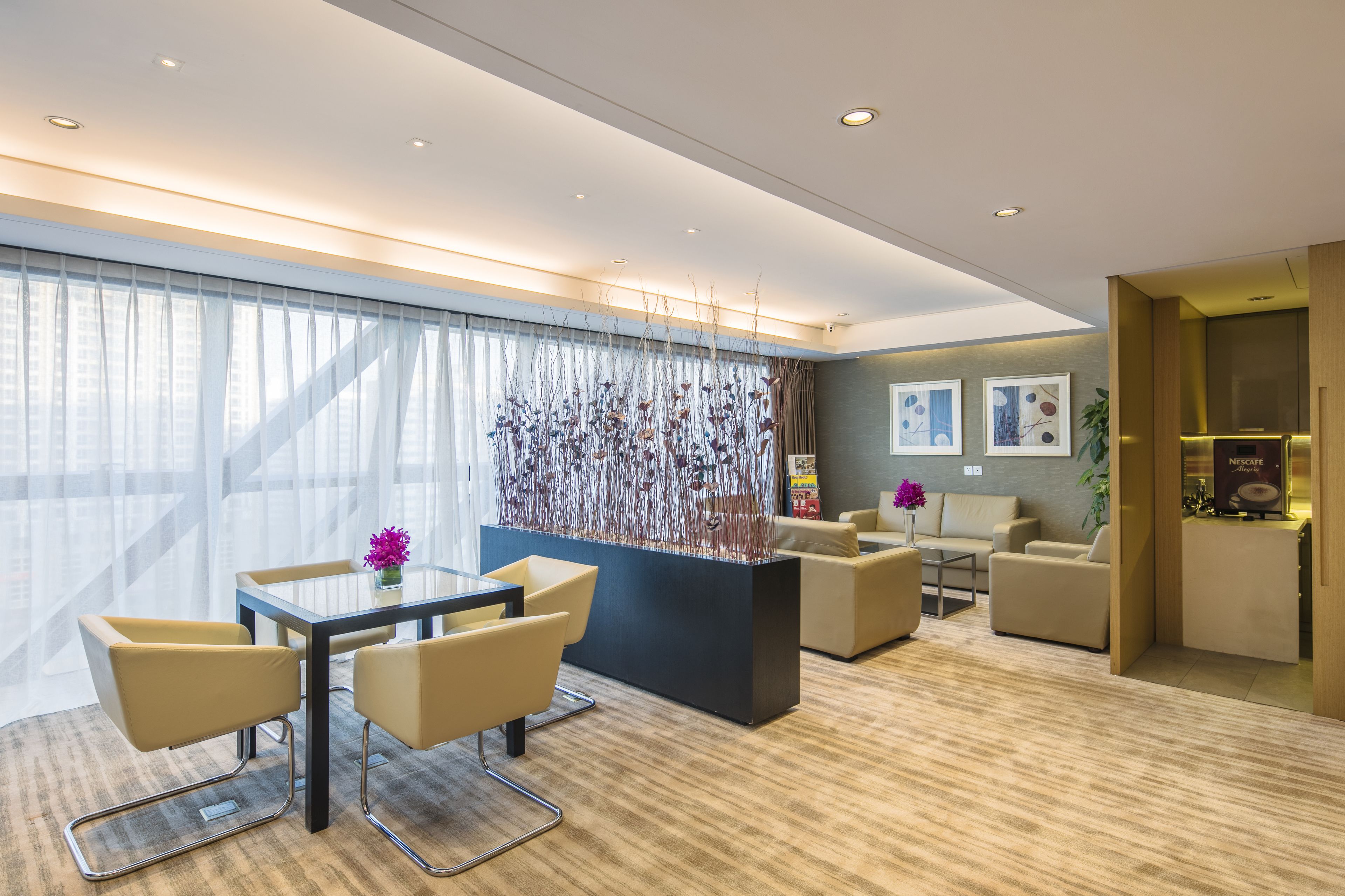 A modern hotel lobby with a reception desk, seating area, and large windows with sheer curtains.