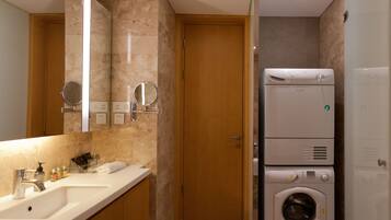 Un baño moderno con lavamanos doble, un espejo, lavadora y una puerta.