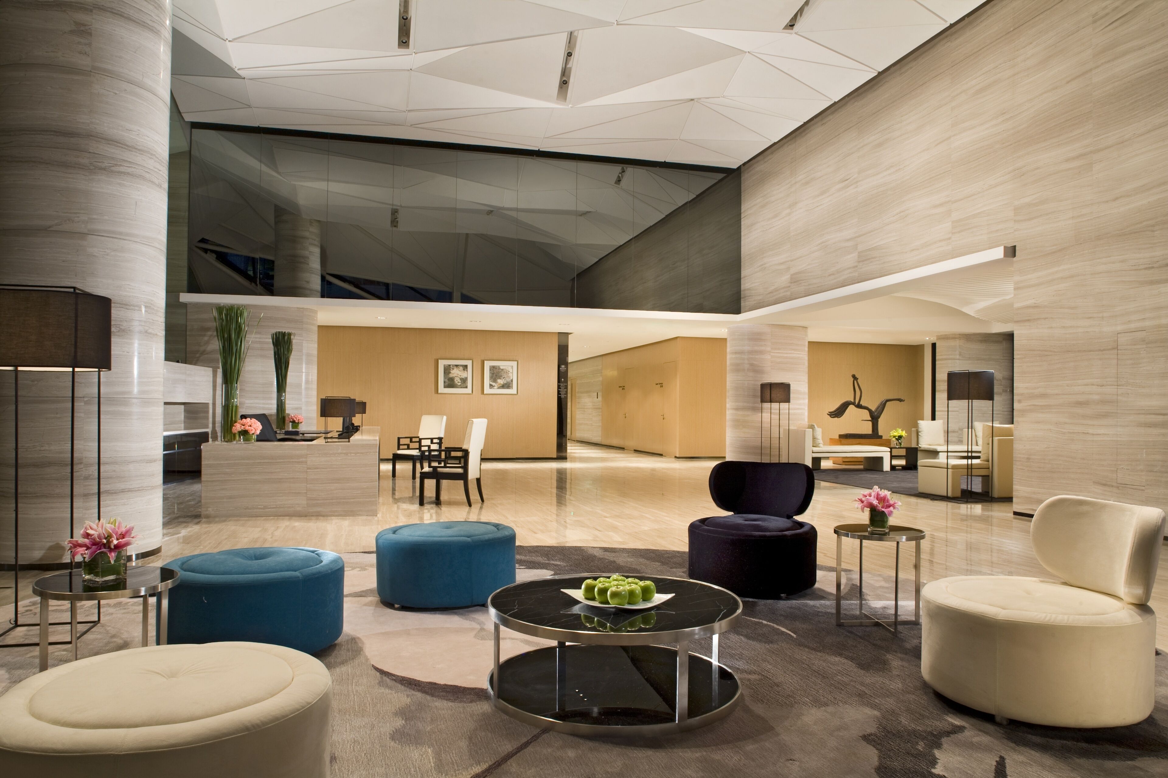A spacious lobby with modern furniture, a reception desk, and a large glass wall.