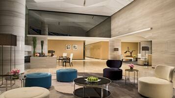 A spacious lobby with modern furniture, a reception desk, and a large glass wall.