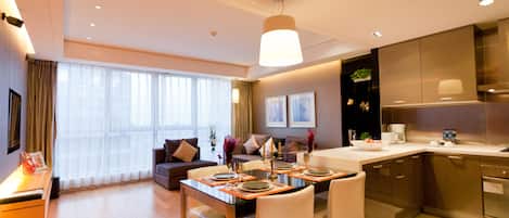 A modern hotel room with a dining area, a sofa, and a kitchen.