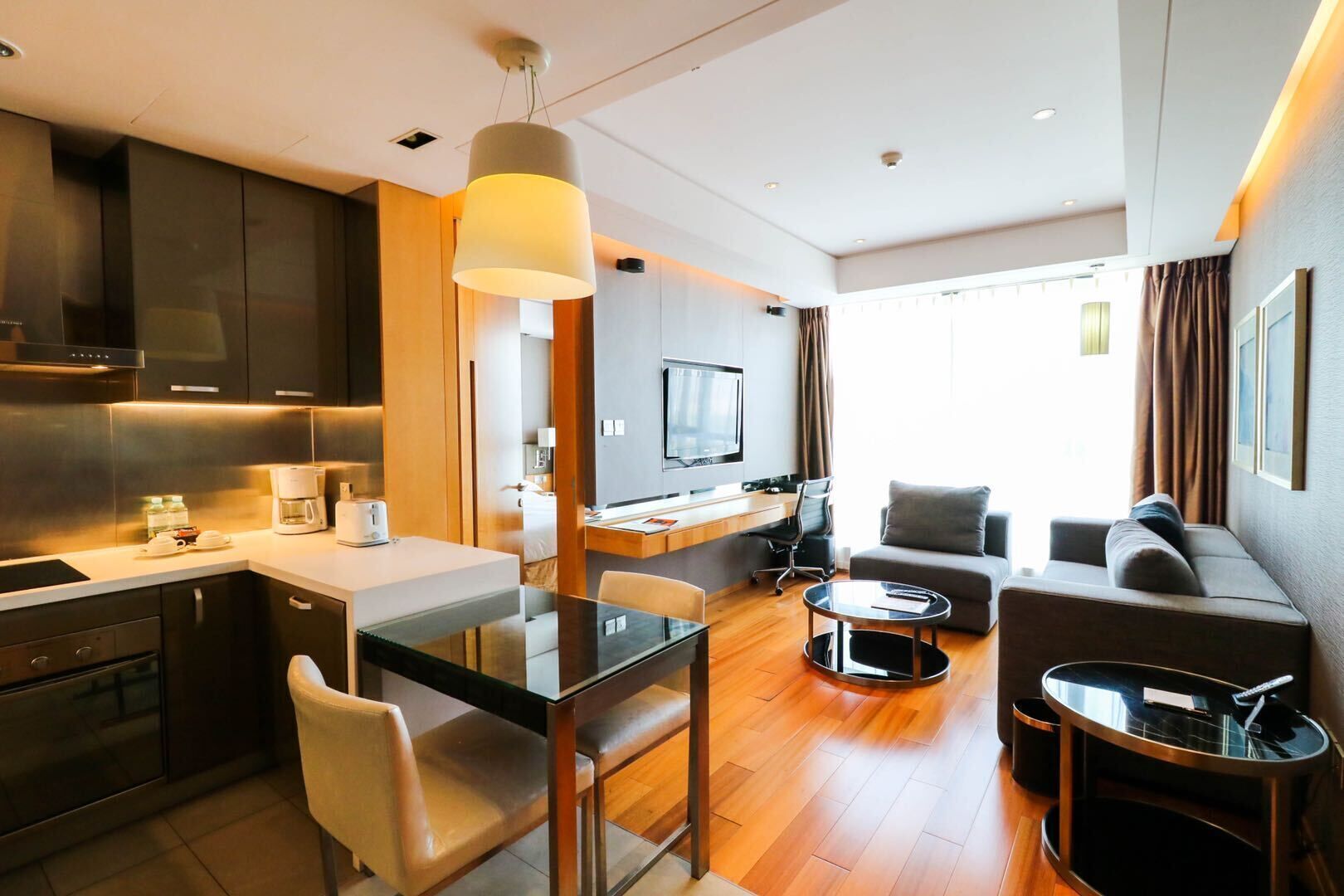 A modern hotel room with a kitchen, dining area, and seating space.