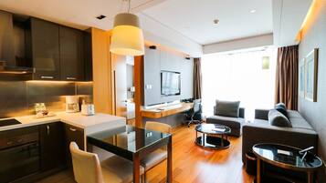 A modern hotel room with a kitchen, dining area, and seating space.