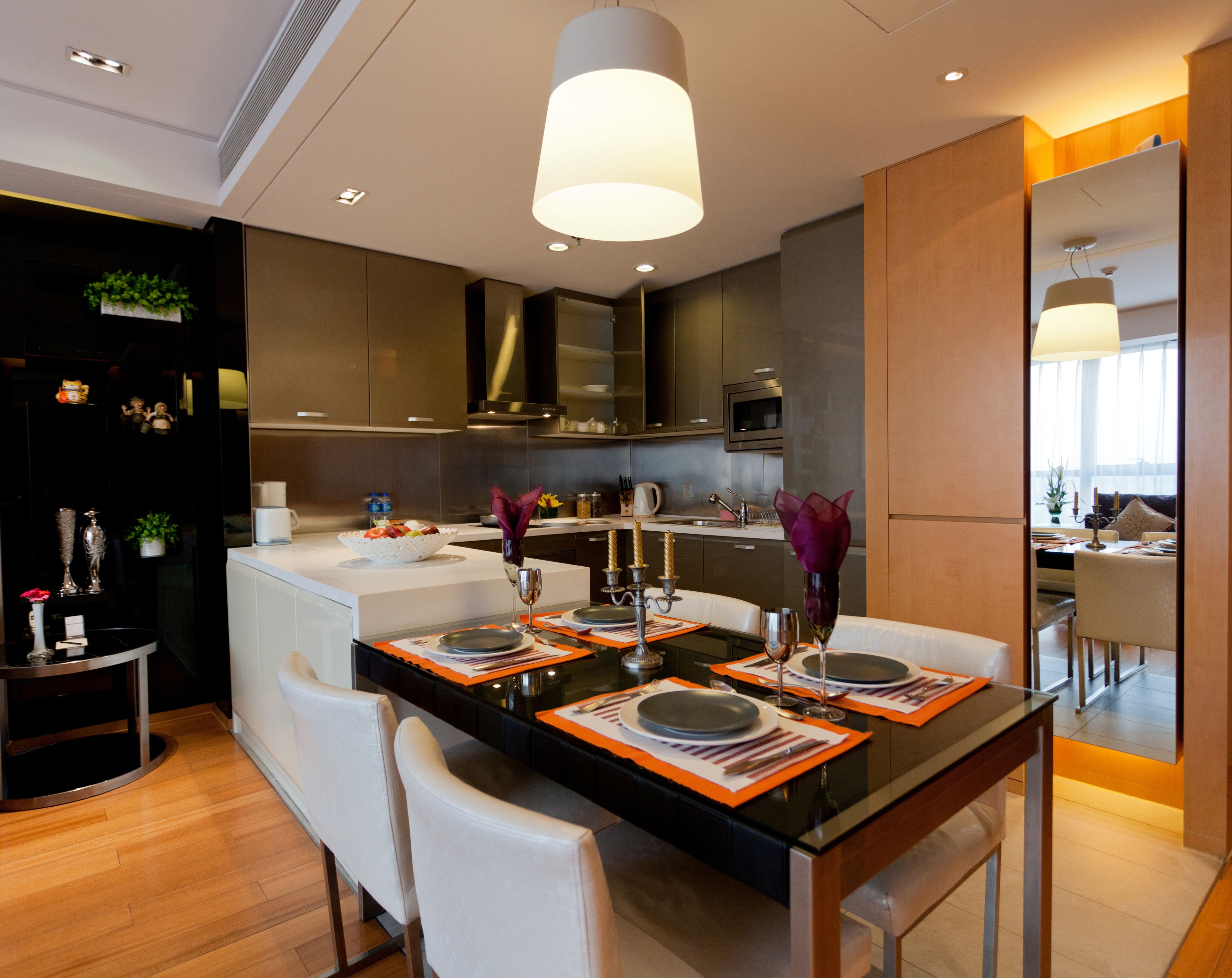 A modern kitchen with a central island, white chairs, and a dining table set for four.