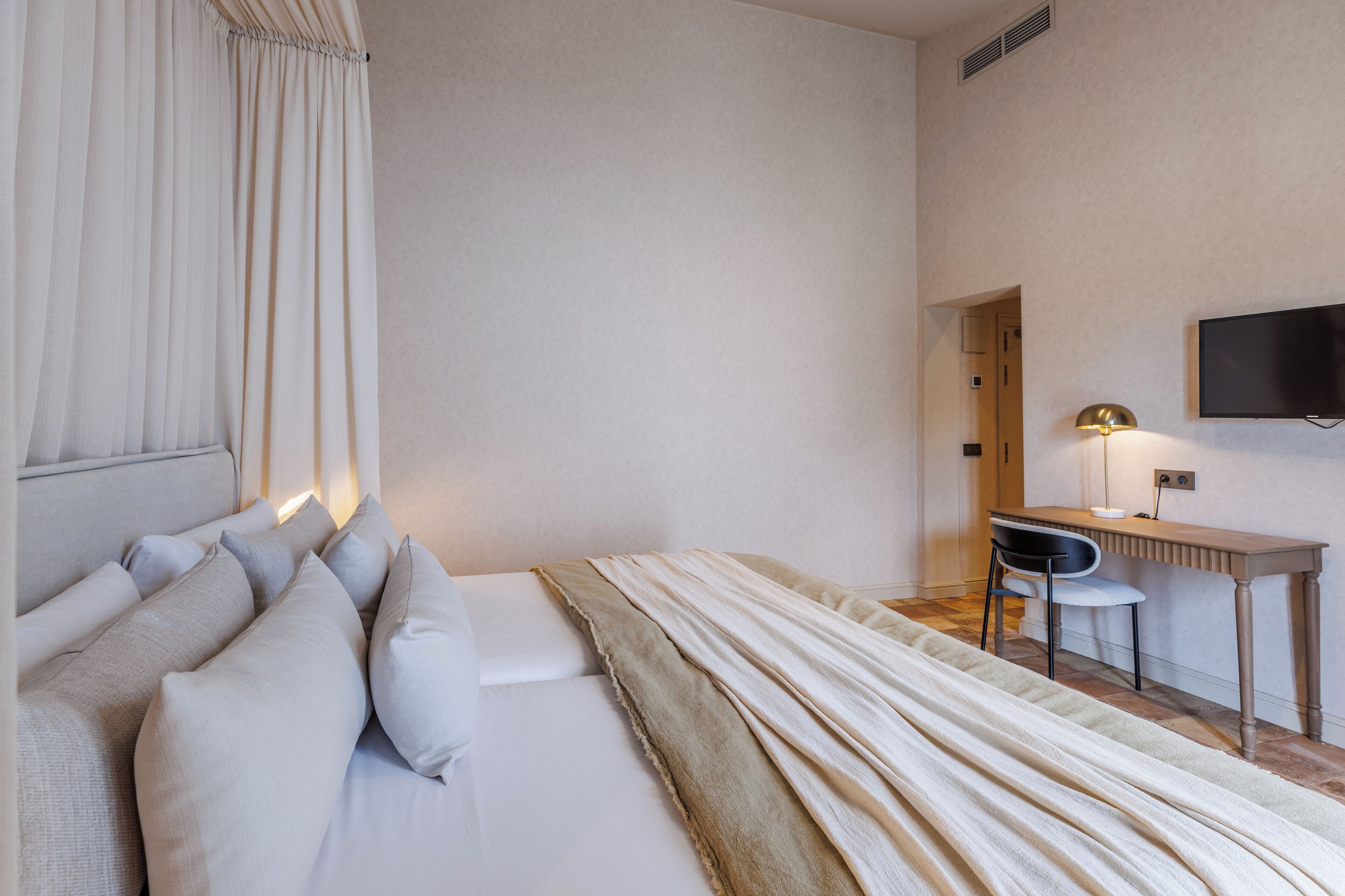 Een hotelkamer met een bed, een bureau, een stoel, een televisie en een lamp.