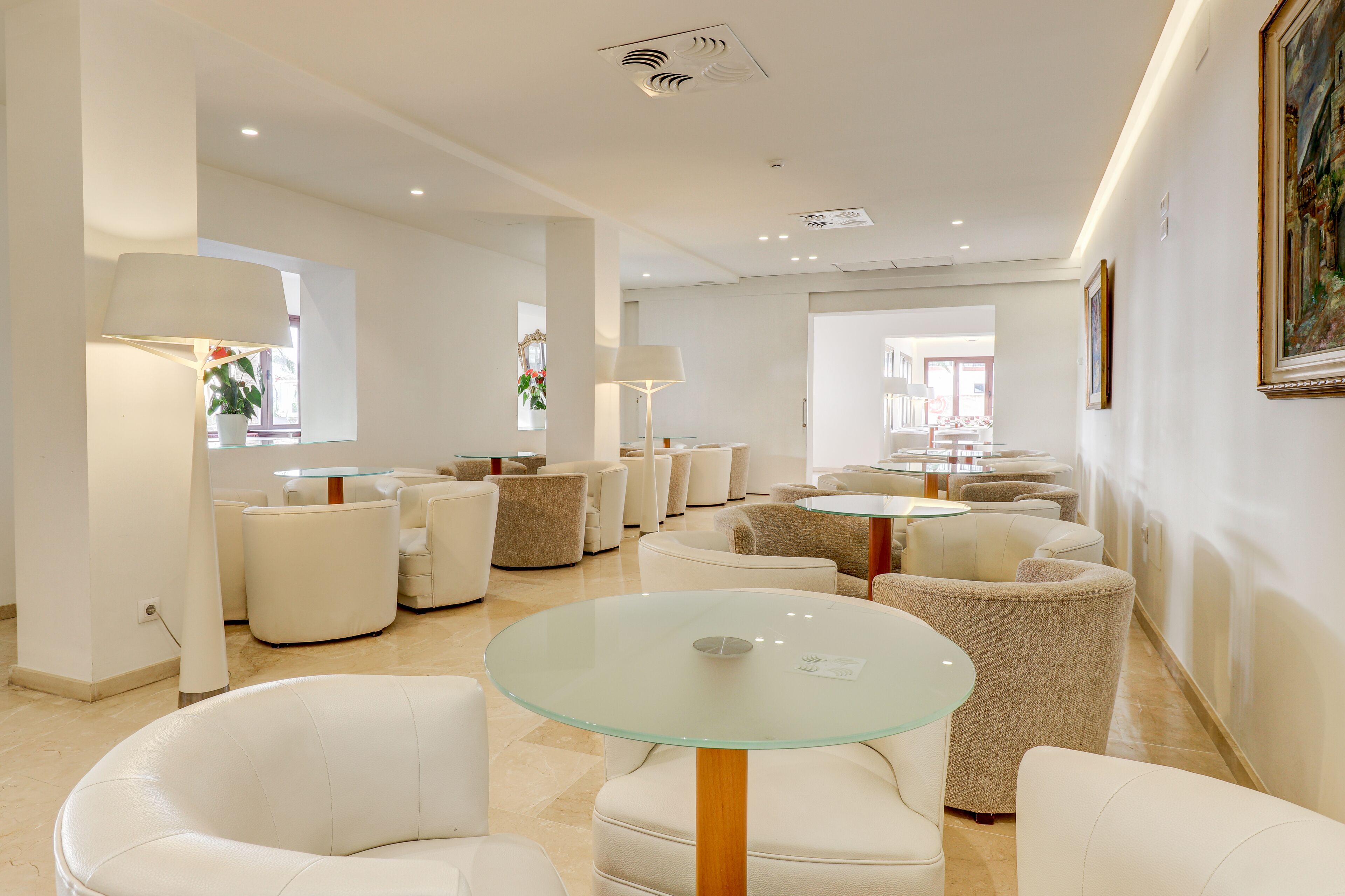 Un espace de détente moderne avec des tables rondes en verre et des canapés en cuir blanc.