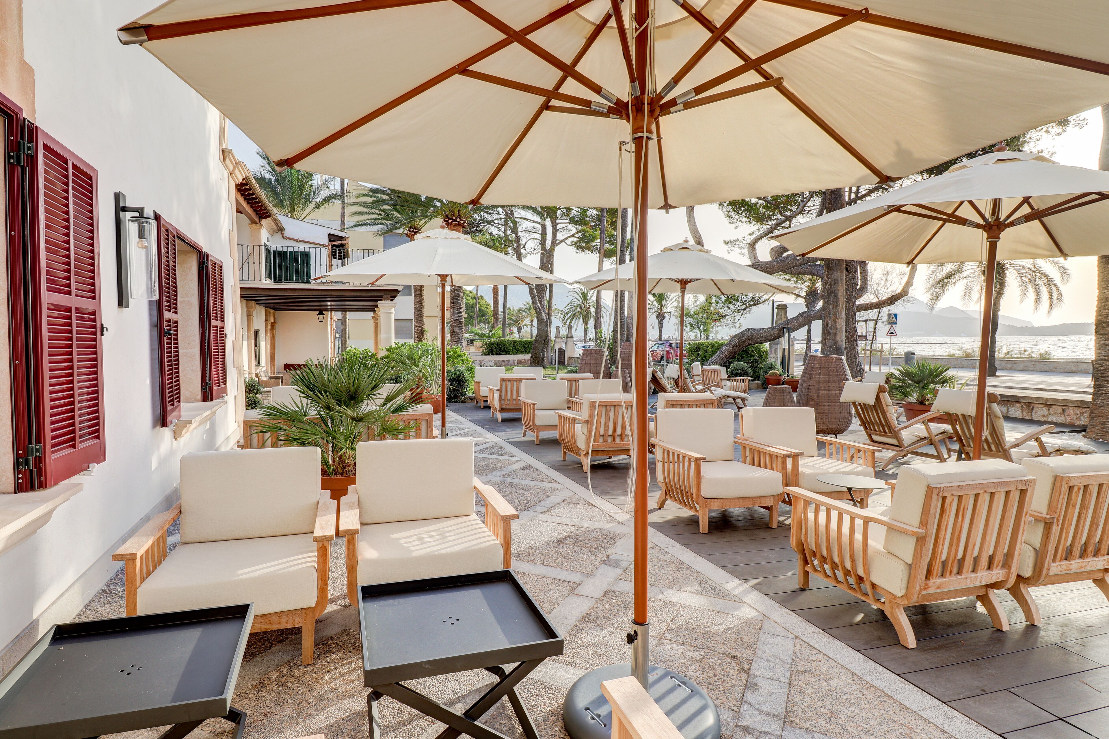 Un espace extérieur aménagé avec des chaises et des tables en bois, des parasols et des plantes en pot.