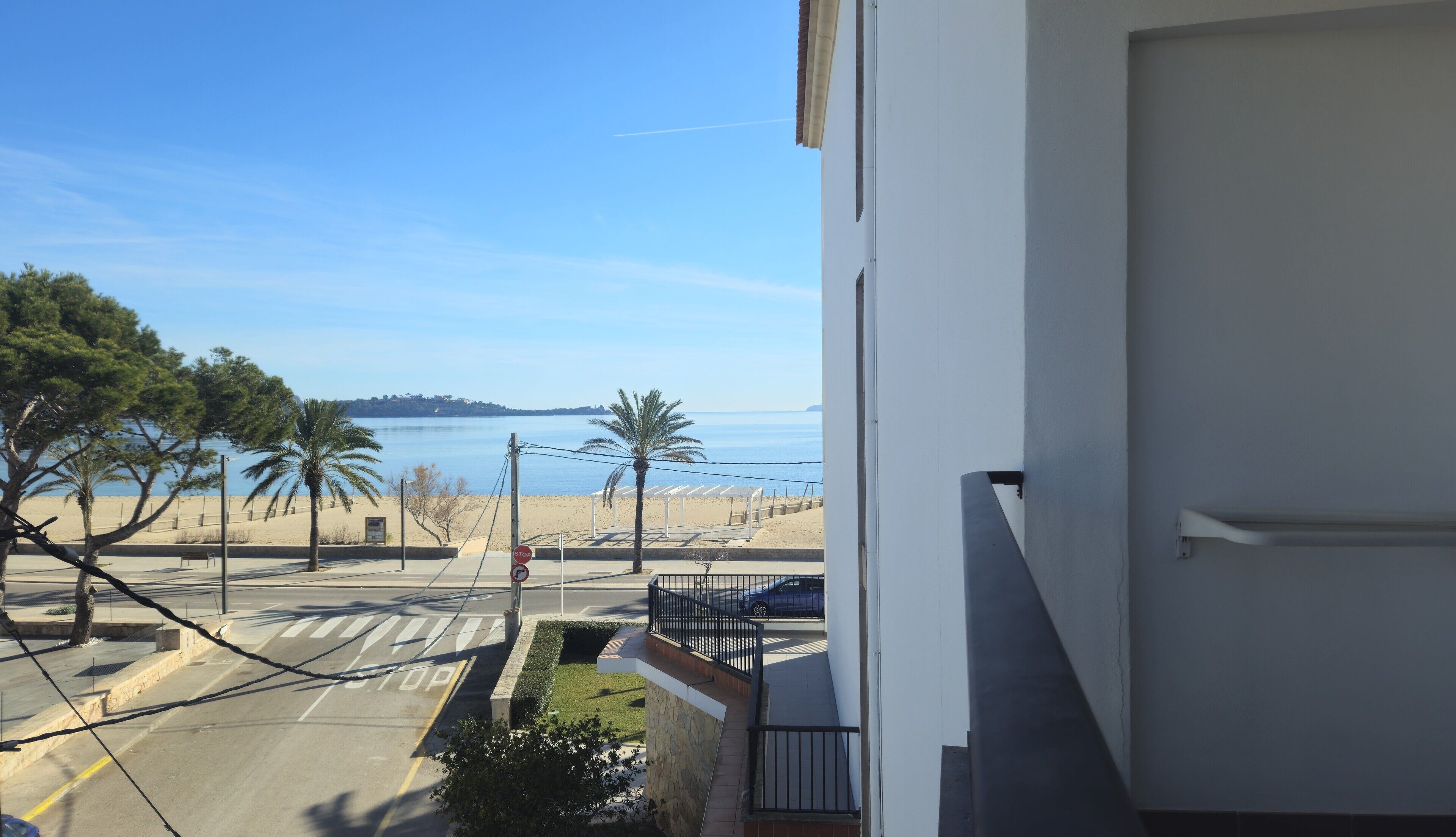 A balcony with a view of a beach and the sea.