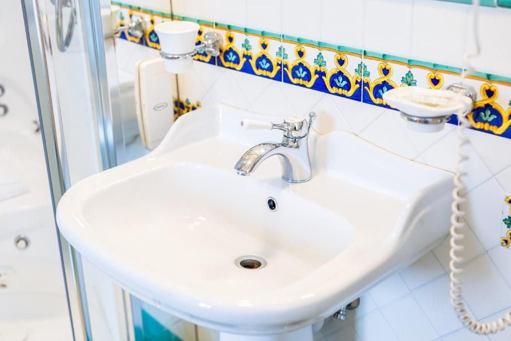 Un lavabo de salle de bain avec un receveur en porcelaine blanche, un robinet chromé et un téléphone fixé au mur.